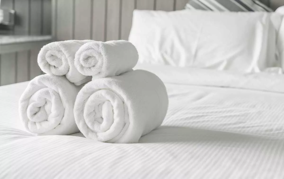 Bade- und Handtücher wurden vom Reinigungspersonal zusammengerollt und auf das Hotelbett gelegt.