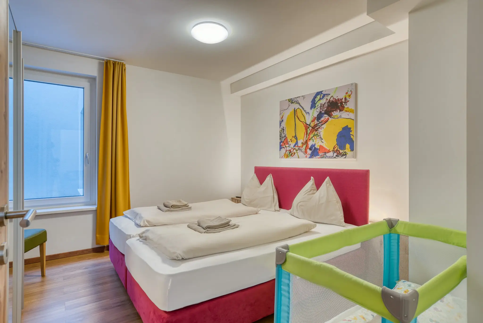 Ein Schlafzimmer mit Babybett im Refugio Apartment im COOEE alpin Hotel in Gosau.