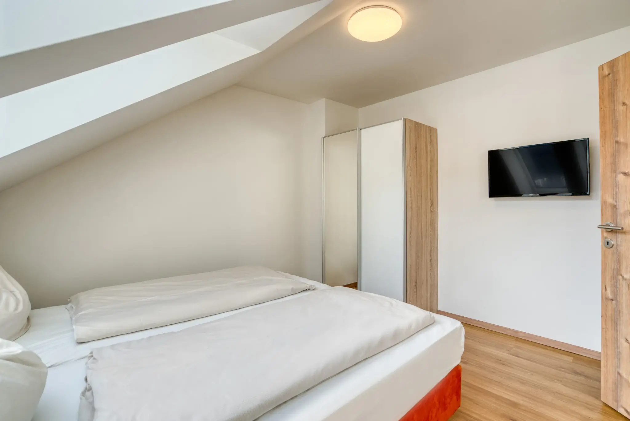 Das Schlafzimmer im 2ten Stock mit TV und Schrank im Rockey Apartment im COOEE alpin Hotel Dachstein in Gosau.