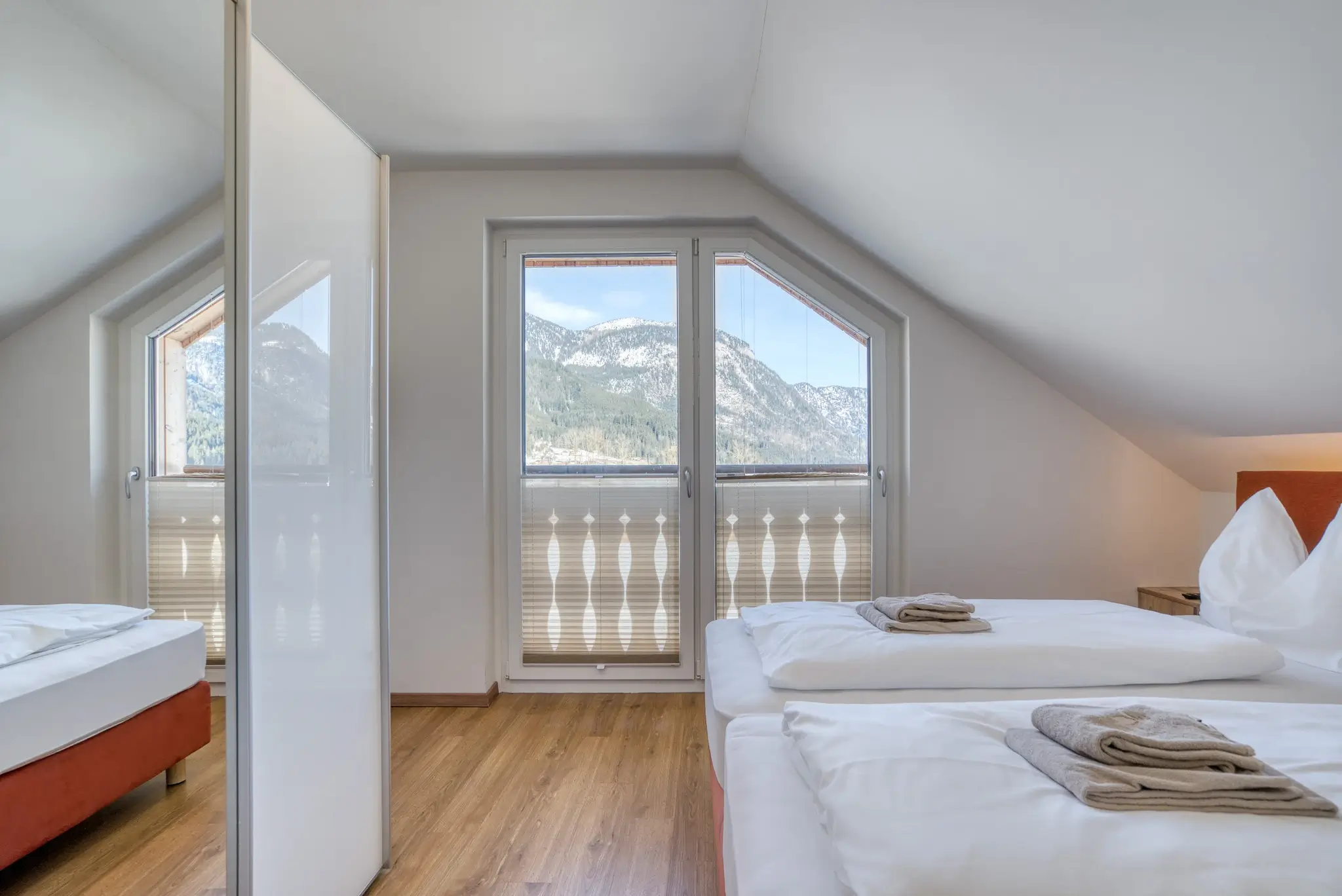 Ein Schlafzimmer mit Balkon im Alpinomad Apartment im COOEE alpin Hotel Dachstein in Gosau.
