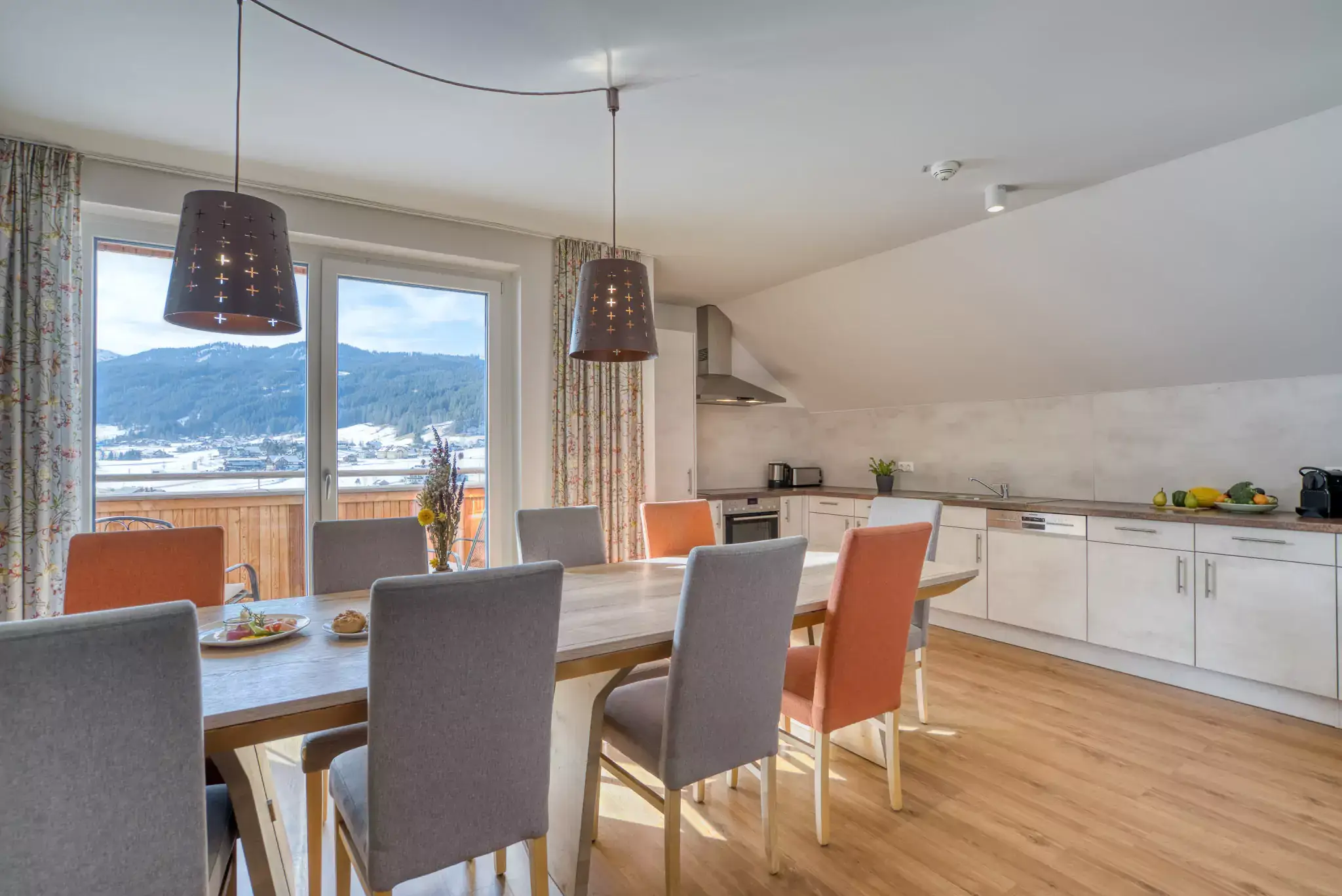 Das Wohnzimmer mit Tisch und Balkon im Gigantos Apartment im COOEE alpin Hotel Dachstein in Gosau.