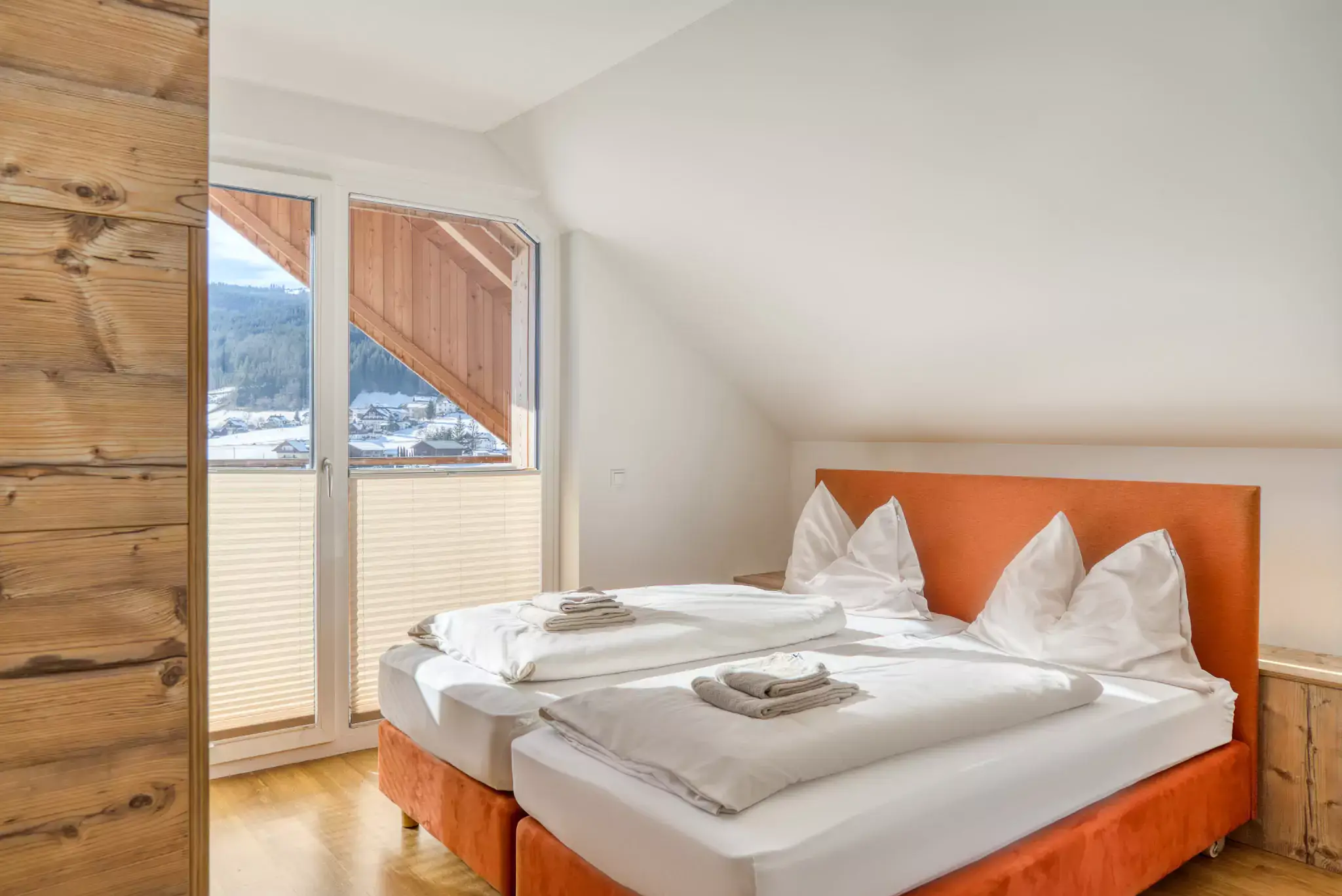 Zimmer mit einem orangenen Doppelbett und einem Etagenbett gegenüber.