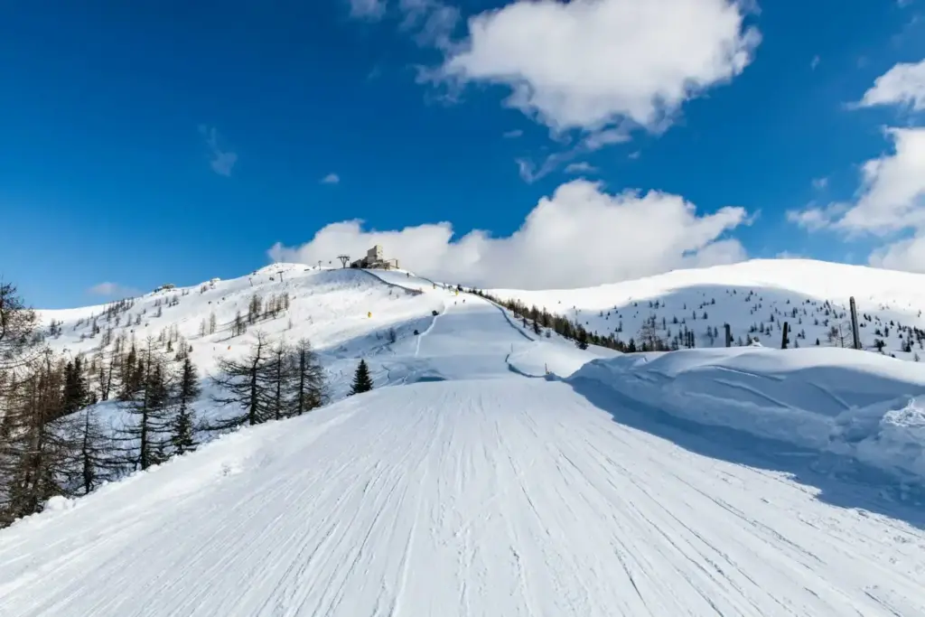 Blick von der Piste auf die Bergstation der Kaiserburgbahn im Winter bei sonnigem Wetter mit blauem Himmel.