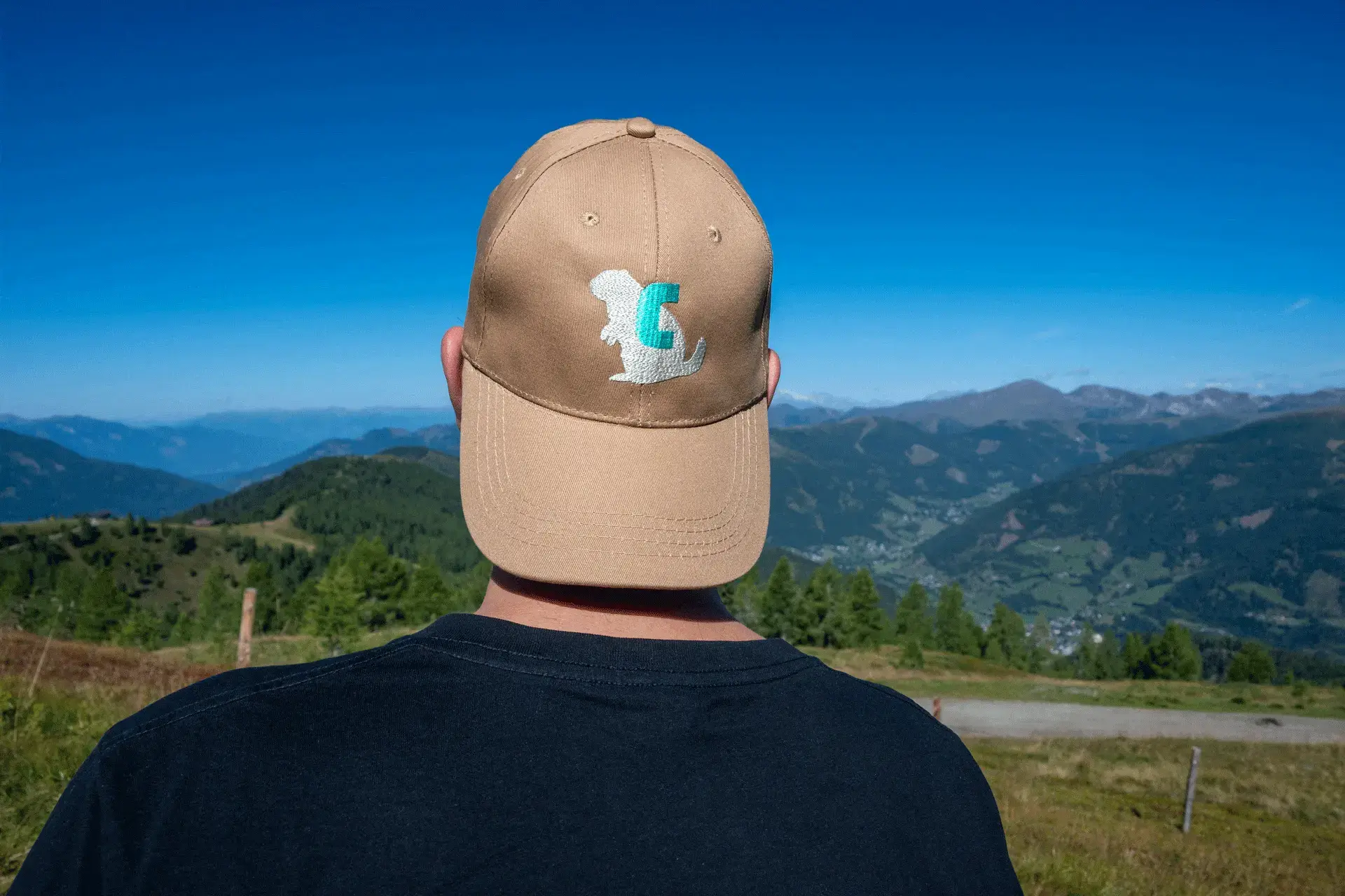 Beige COOEE alpin Cap „Alinga“ mit Sticklogo, getragen bei einer Wanderung in den österreichischen Alpen – stylische Outdoor-Kappe als Sonnenschutz und praktisches Accessoire für Abenteuer in den Bergen.