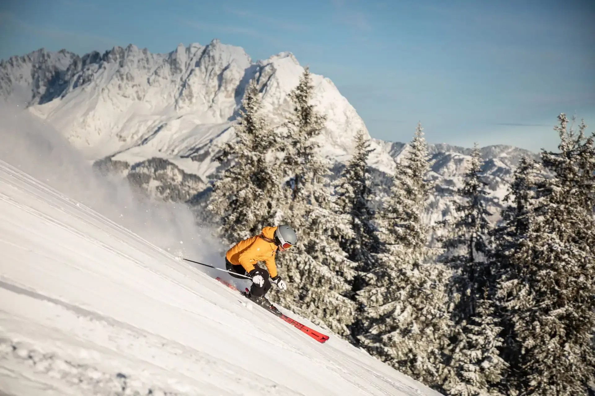 Skifahrer auf sonniger Piste in St. Johann in Tirol mit Blick auf den Wilden Kaiser – perfekter Skiurlaub in den Kitzbüheler Alpen mit Pulverschnee, Panorama und Wintersportgenuss.