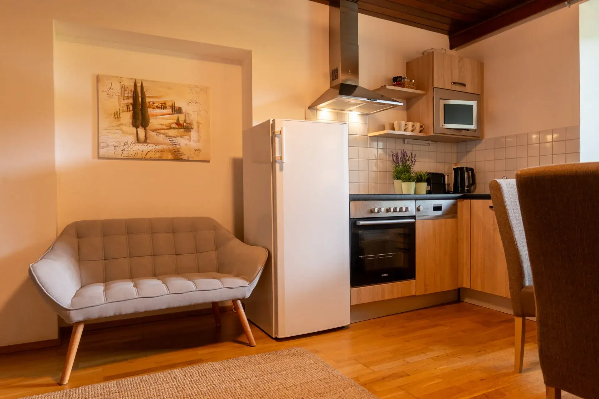 accogliente zona soggiorno/pranzo con cucina moderna completamente attrezzata, comprensiva di piano cottura in vetroceramica, forno e microonde, frigorifero capiente, divano grigio e tutti gli utensili da cucina necessari