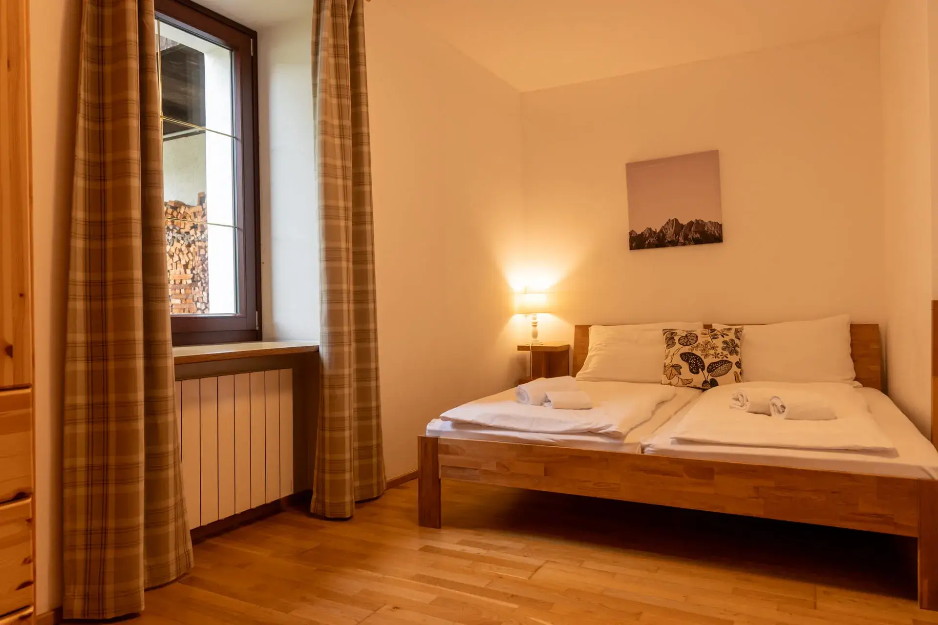 camera da letto luminosa con un comodo letto matrimoniale, ampia finestra con tende lunghe, radiatore presente