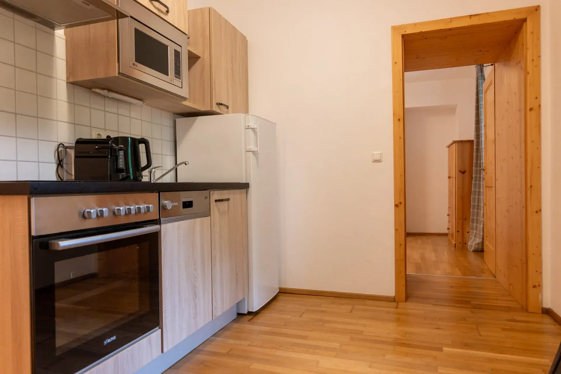 Cucina completamente attrezzata nell'appartamento Toplitzsee a Gosau, con piano cottura, forno, frigorifero, macchina per il caffè e bollitore.