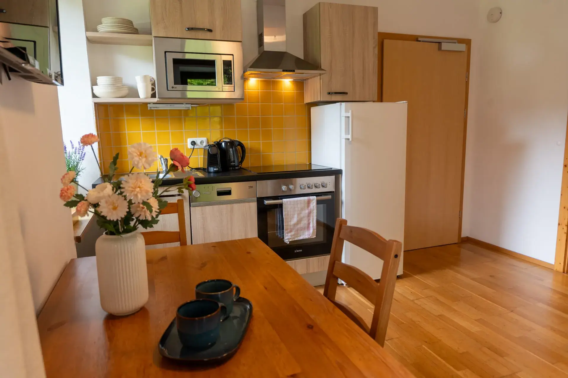 Hangulatos étkező és modern konyha a Gosau-i Hallstätter See apartmanban, tűzhellyel, sütővel, hűtőszekrénnyel, kávéfőzővel és mikrohullámú sütővel.