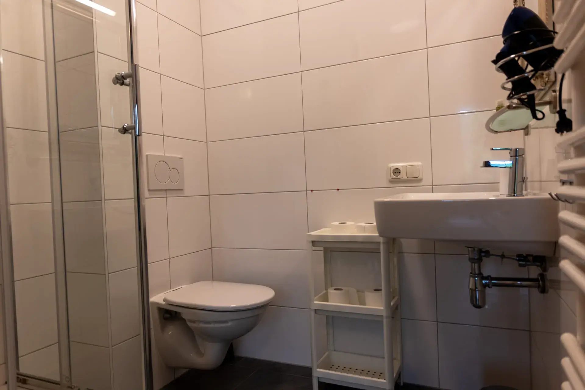 Moderní koupelna v apartmánu u jezera Traunsee v komplexu Ulmenhof se sprchou, toaletou a umyvadlem.