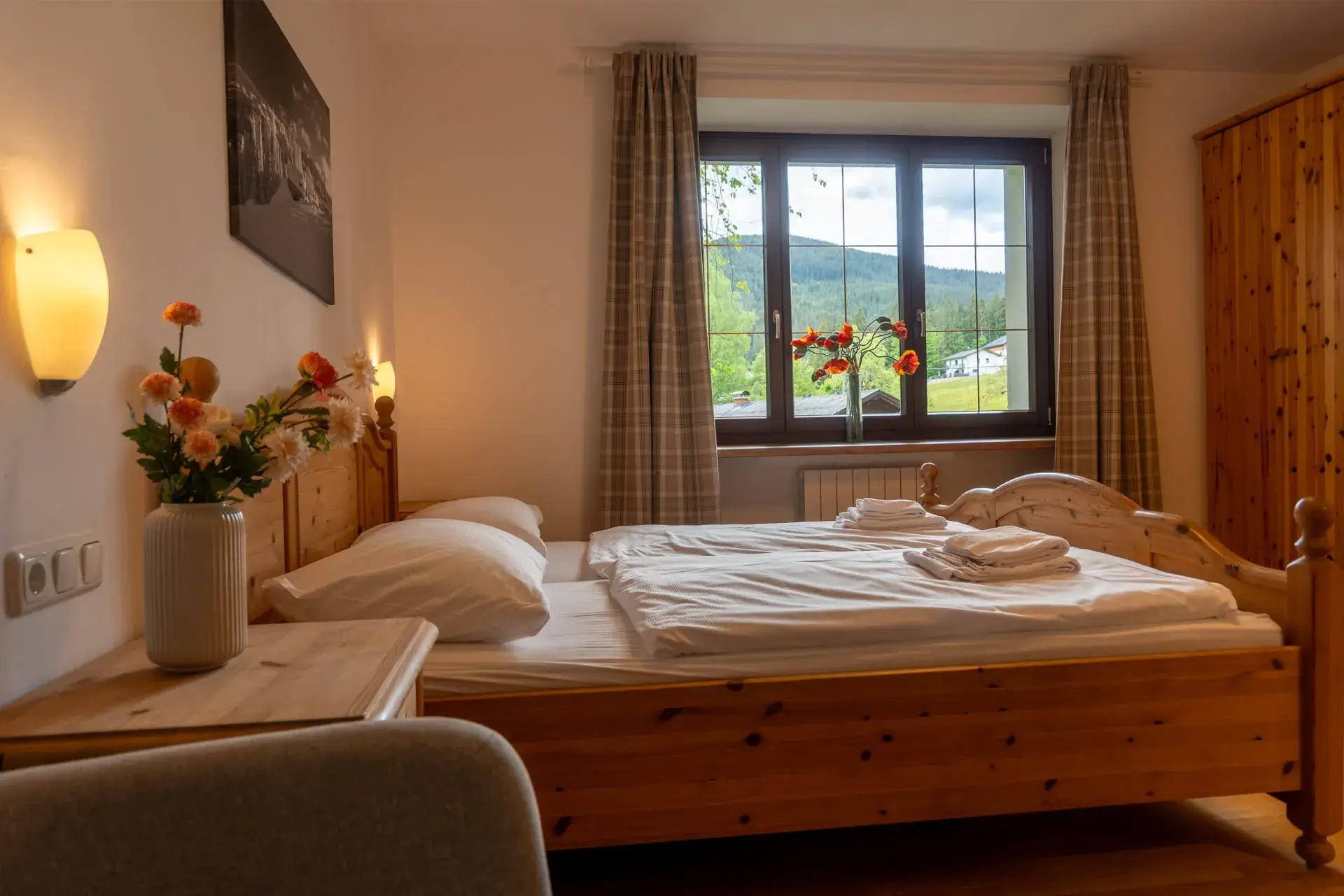 Luminosa camera da letto nell'appartamento sul Traunsee a Gosau, con letto matrimoniale, ampia finestra e vista sul paesaggio montano circostante.