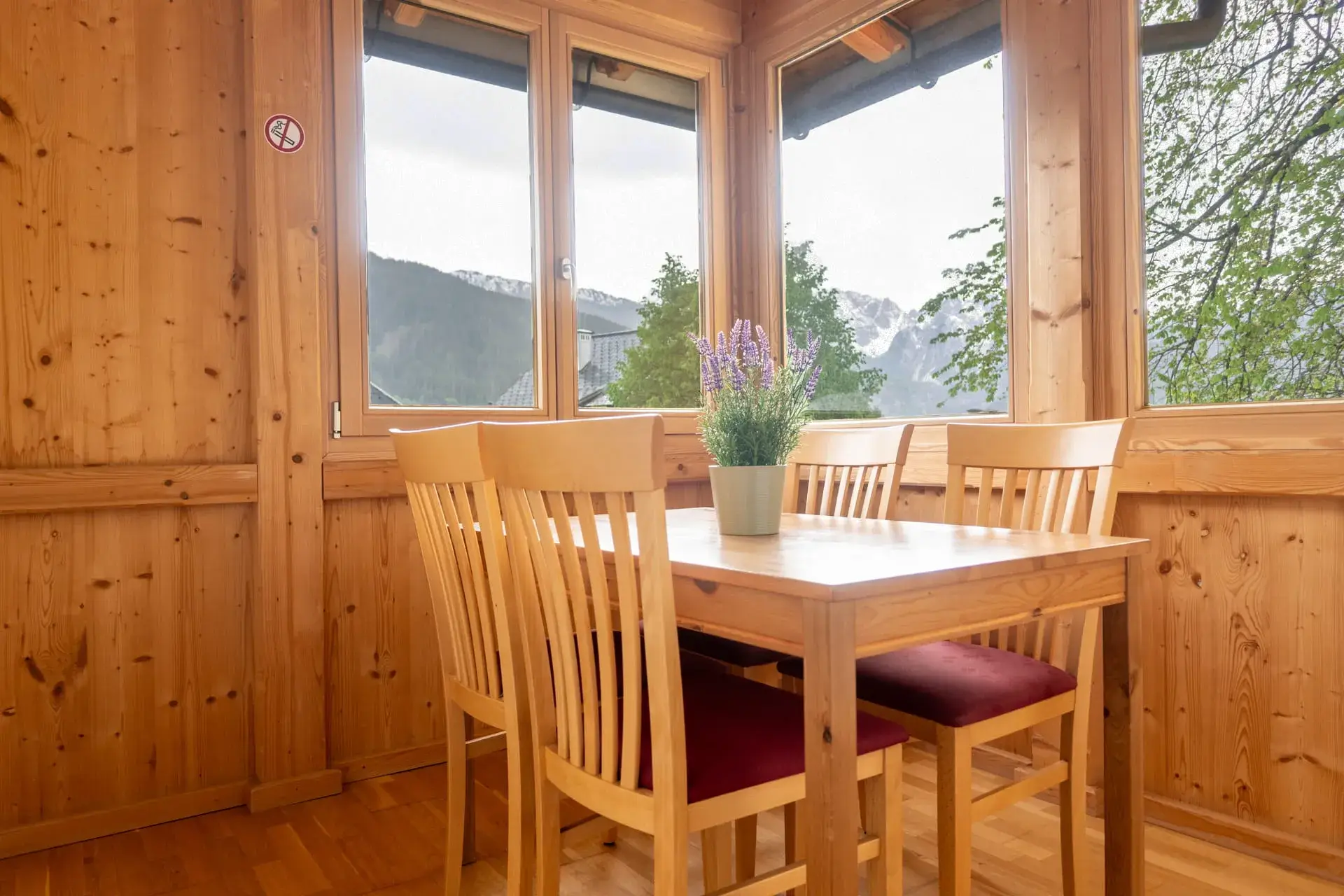 Accogliente zona pranzo nell'appartamento Wolfgangsee dell'Ulmenhof, con finestre panoramiche e vista sul paesaggio montano che circonda Gosau e il Dachstein.