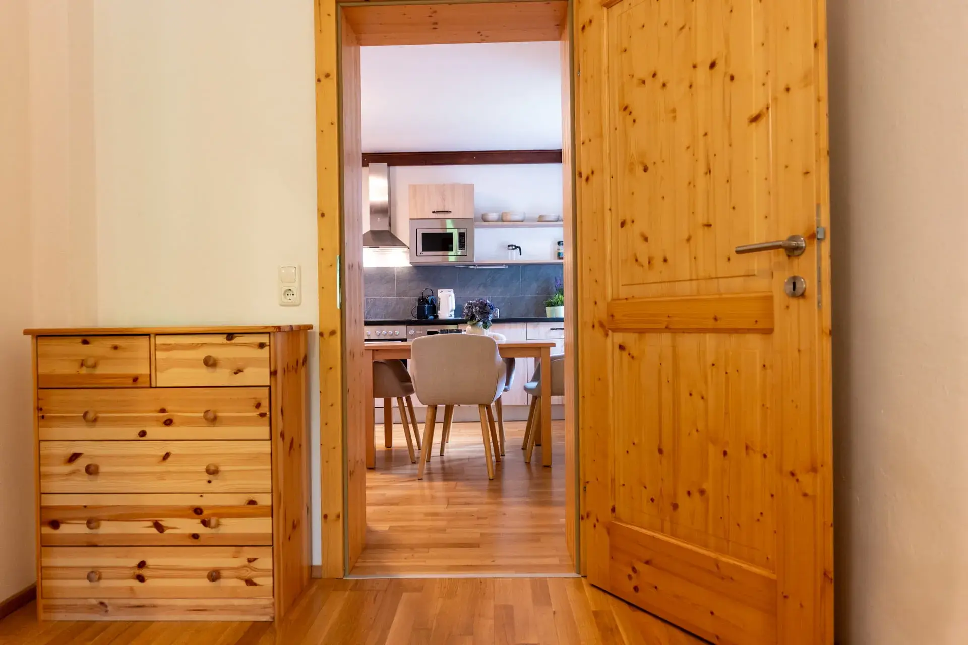 Pohled z ložnice do moderní kuchyně s obývacím prostorem v apartmánu Almsee v Gosau – prostorný prázdninový apartmán v Salzkammergutu.